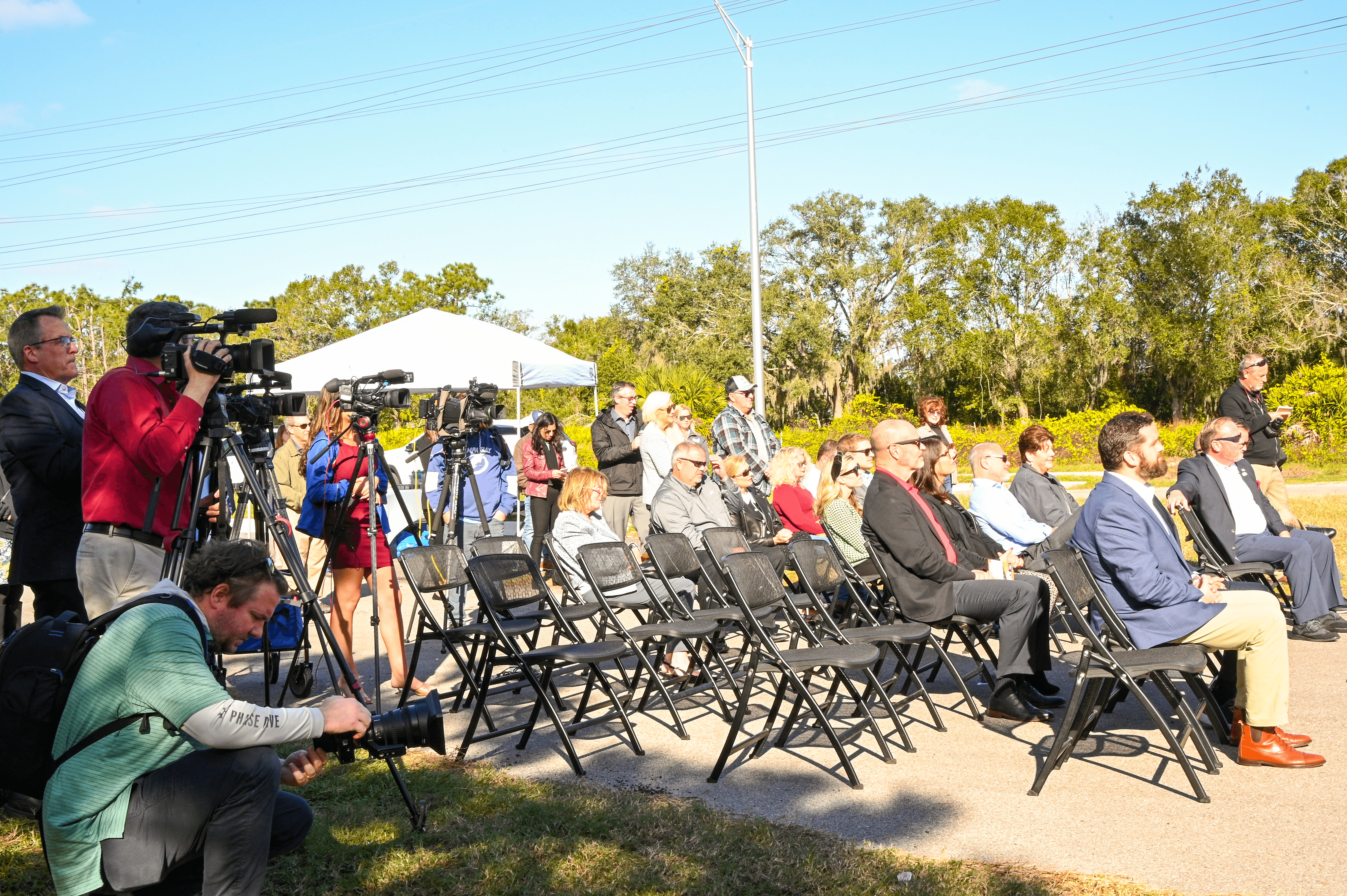 A seated audience and photographers documenting the event